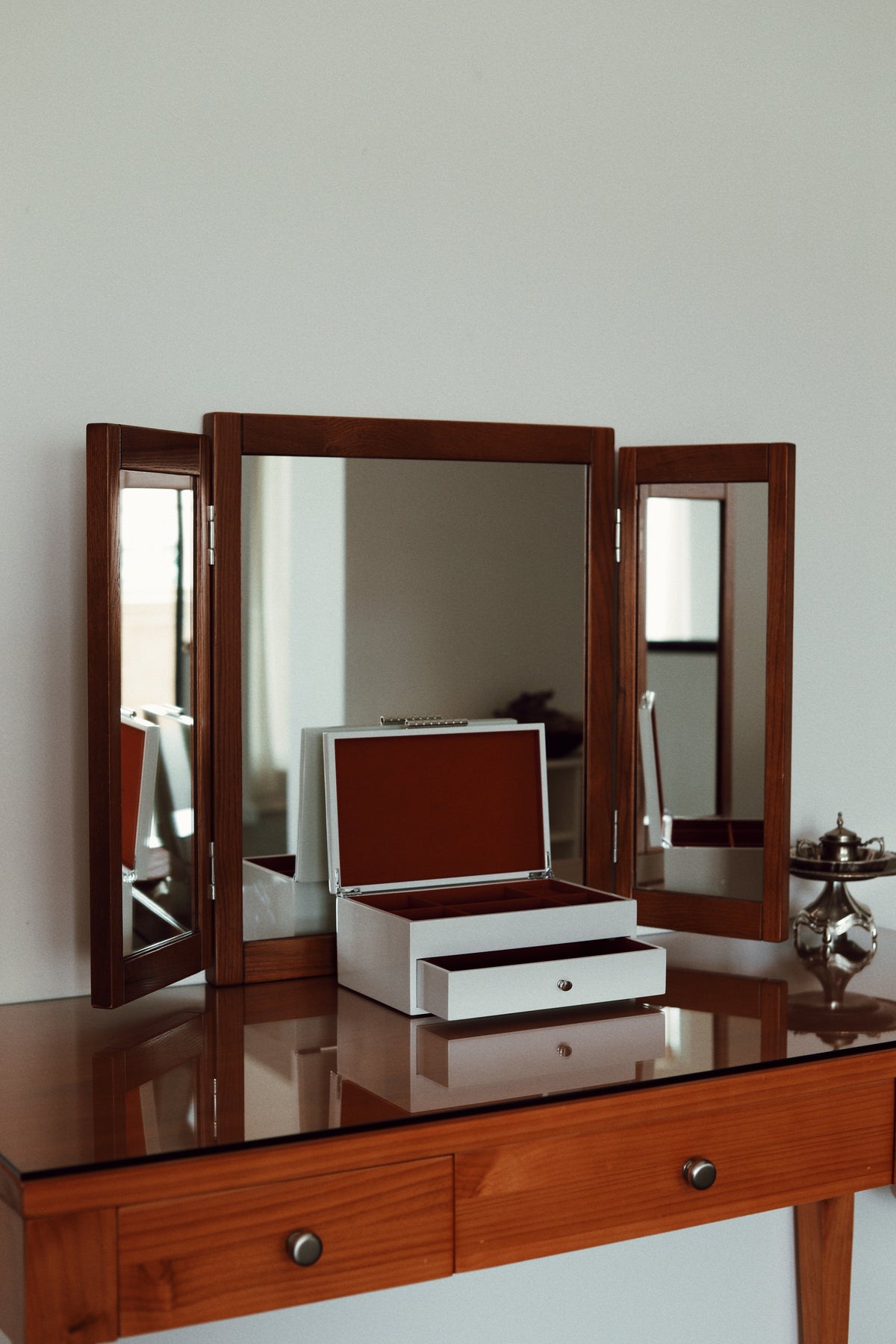 High-gloss white lacquered multi-tiered jewellery organiser with rich contrast velvet interior lining. Vinidec white lacquered tiered jewellery box with open lid and drawer styled on a wooden dressing table