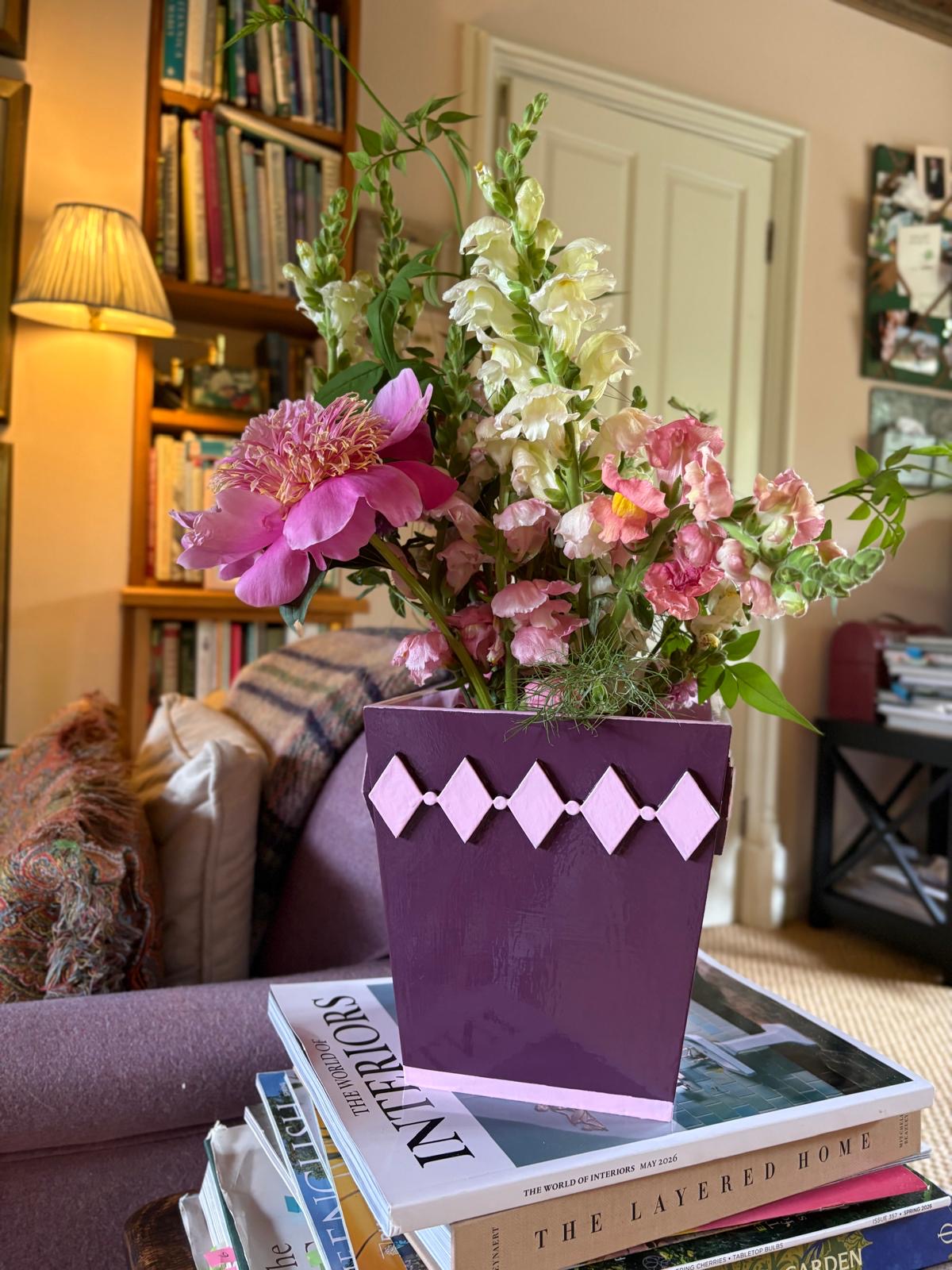 Hand-painted mulberry diamond style planter with a pink edge holding fresh flowers on a coffee table in a colourful home