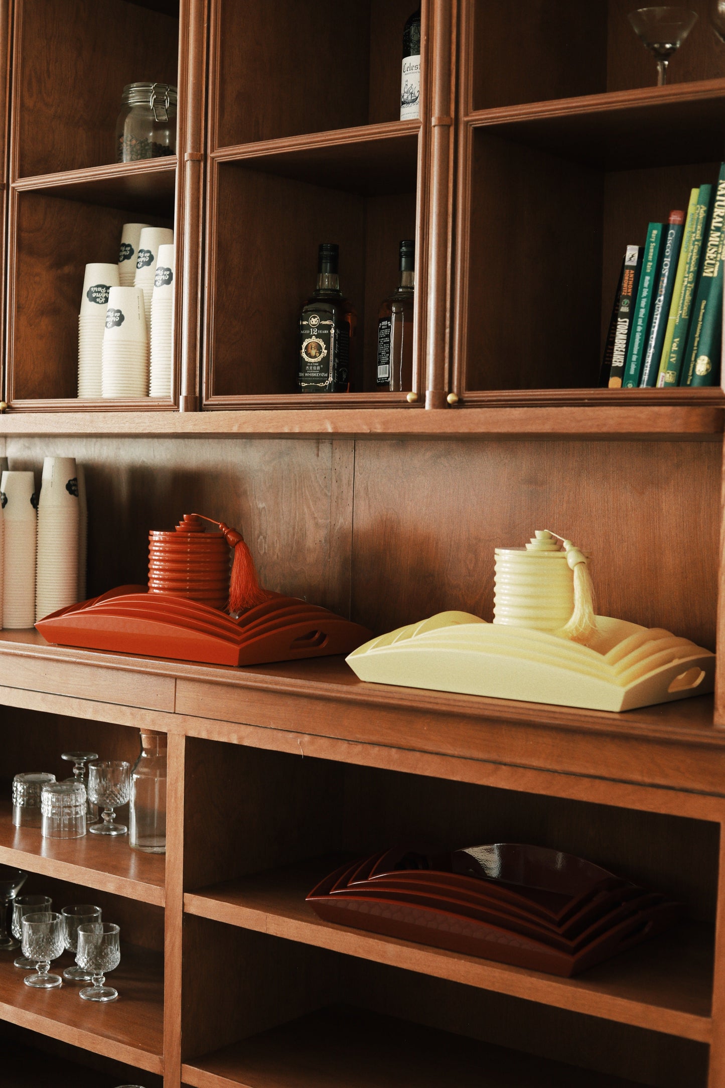 Vinidec medium curvy serving trays in orange and butter yellow, displayed on a wooden shelving unit with matching lantern ice buckets