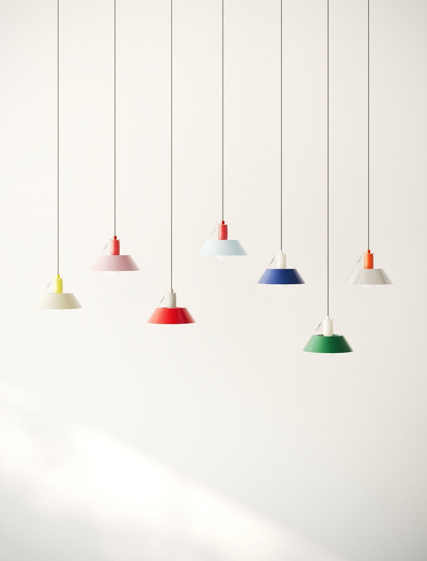FIFTY FIFTY Lamp group of seven colorful pendant lamps with metal shades hanging against a white wall.
