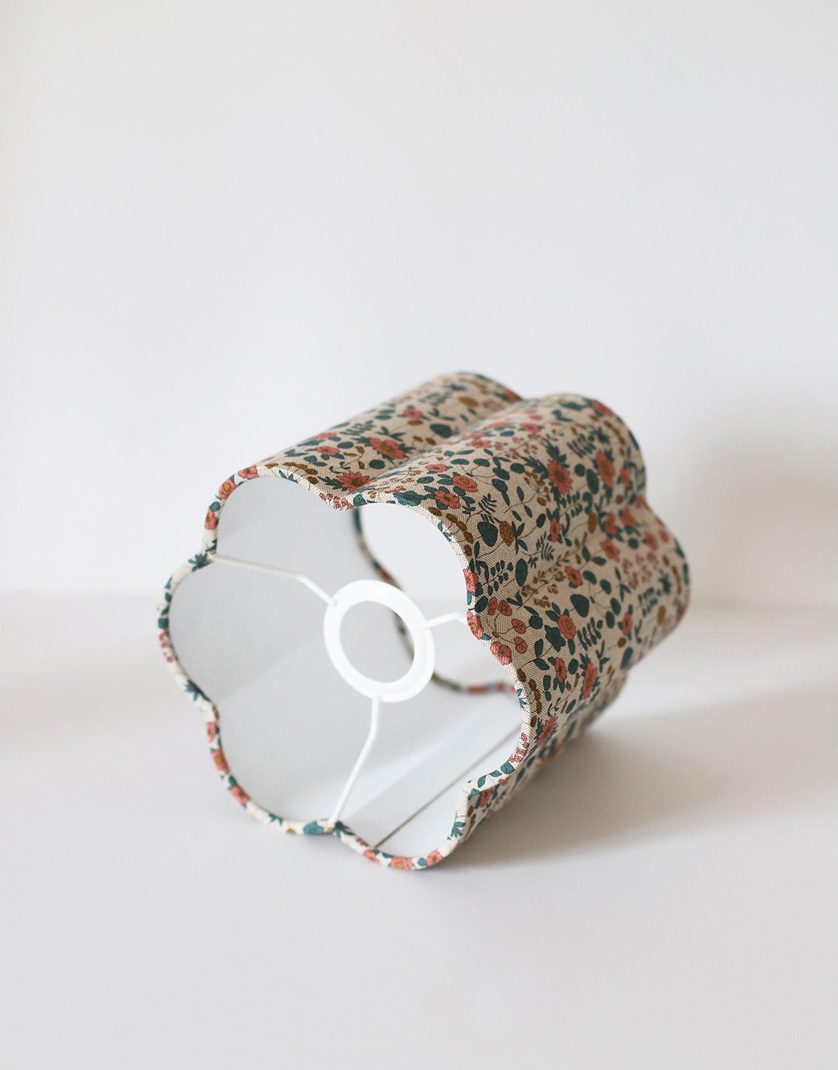 Abat-jour floral beige en coton, motif fleurs colorées, fait main, structure cylindrique avec’ouverture circulaire.