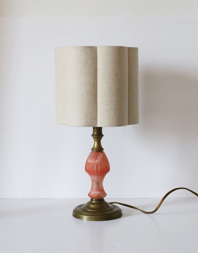 Lampe de table vintage avec pied en verre rose coral et base dorée, abat-jour crème uni en forme fleur.