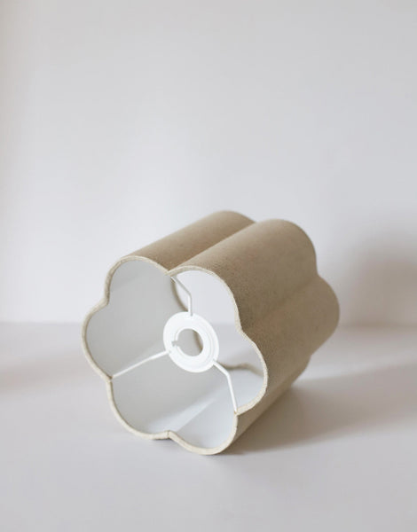 Abat-jour forme fleur uni Flora « classic » en tissu beige posé sur une surface blanche.