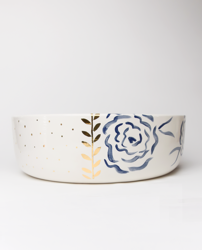 A handmade ceramic salad bowl with royal blue patterns and gold details on the rim.