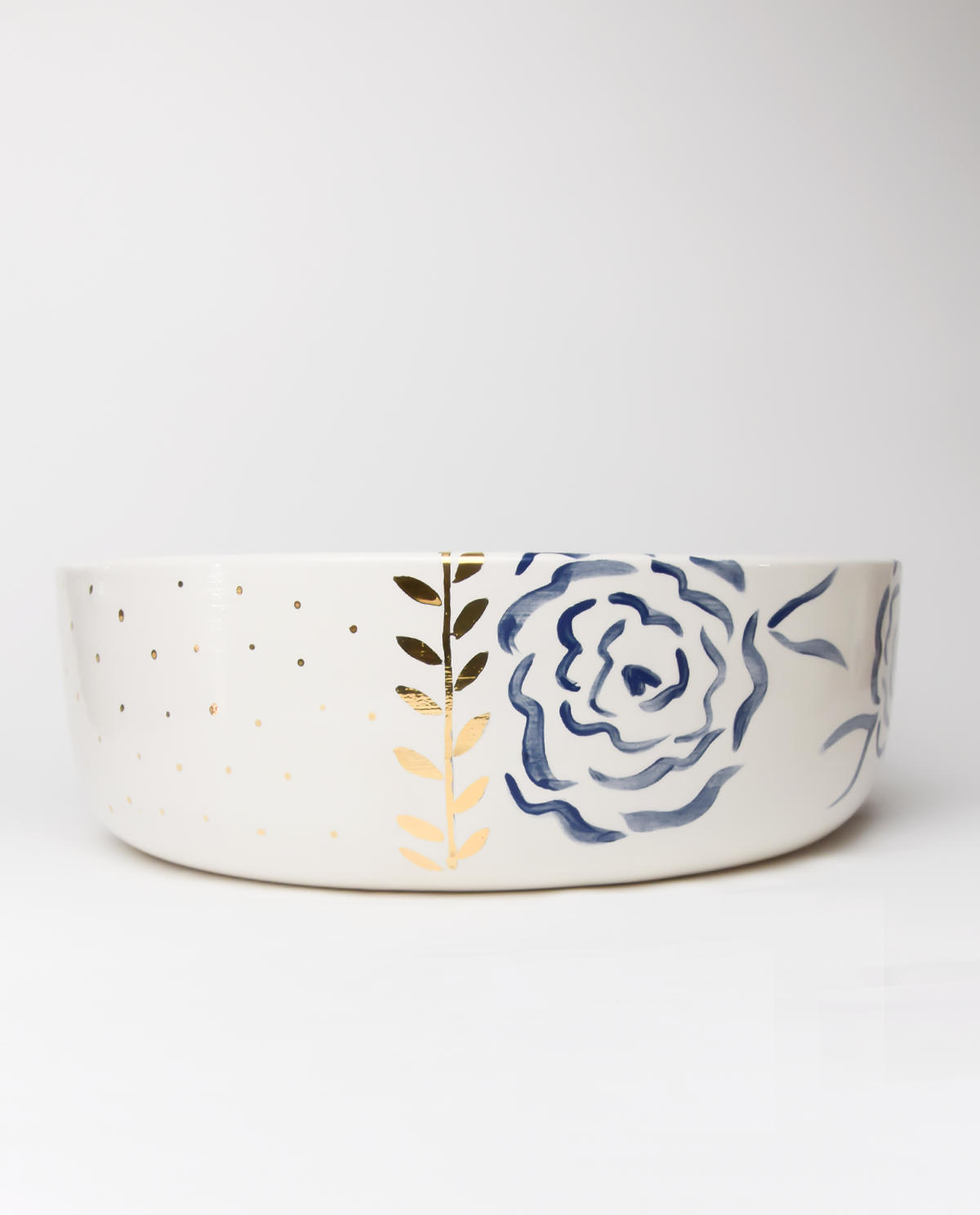 A handmade ceramic salad bowl with royal blue patterns and gold details on the rim.