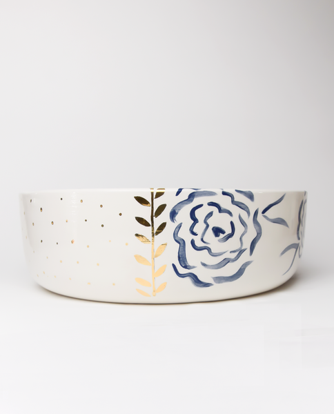 A handmade ceramic salad bowl with royal blue patterns and gold details on the rim.