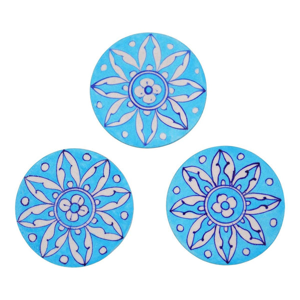 Three round ceramic coasters with blue floral patterns, set against a white background.