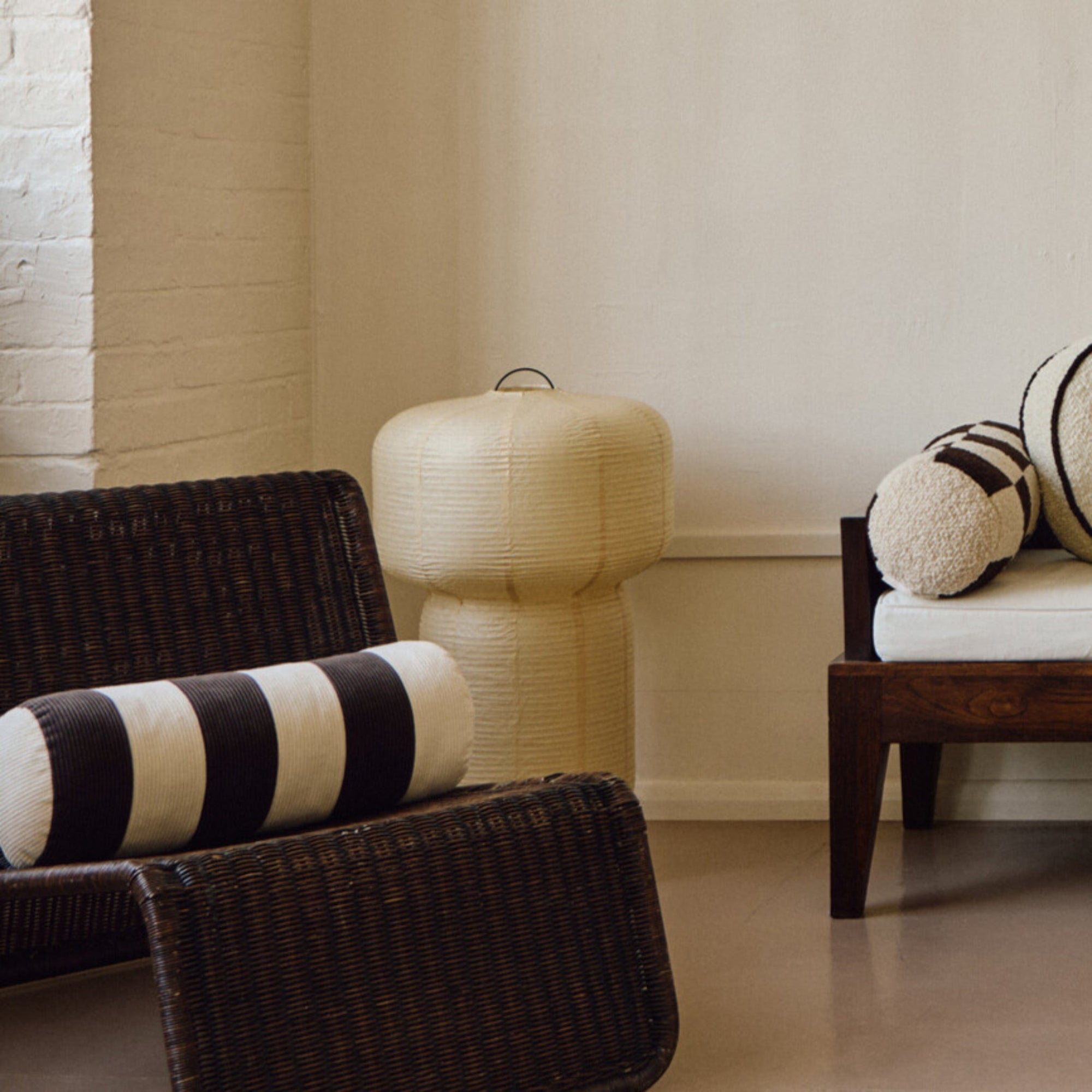 Lifestyle shot of cream and brown cotton corduroy checkered square cushion on wavy rattan chair