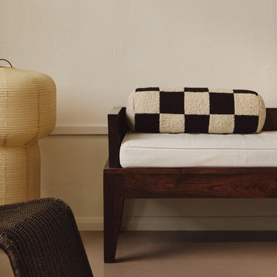 Lifestyle shot of cream and brown wool bouclé checkered bolster cushion on daybed