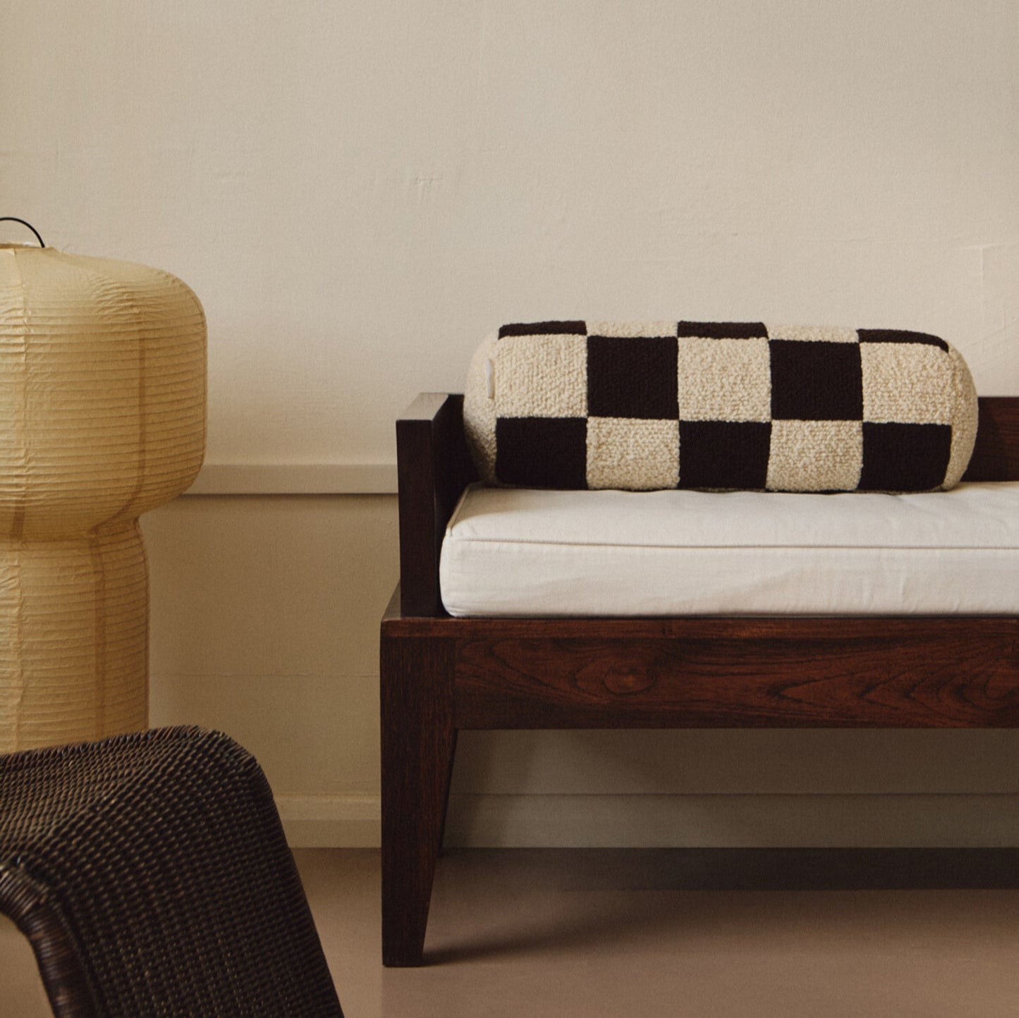 Lifestyle shot of cream and brown wool bouclé checkered bolster cushion on daybed