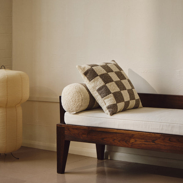 Lifestyle shot of cream and beige wool bouclé checkered square cushion on daybed