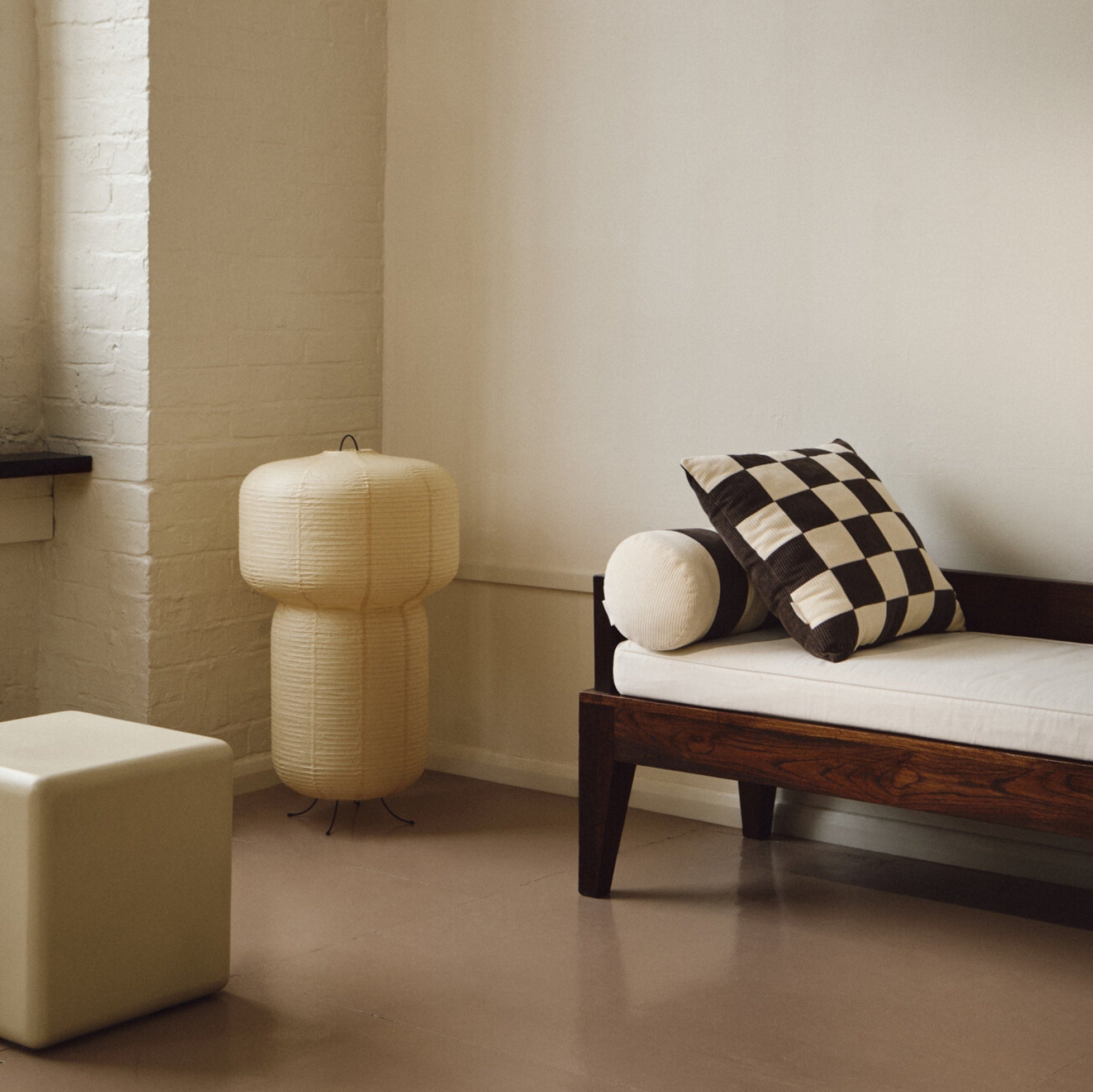 Lifestyle shot of cream and brown cotton corduroy checkered square cushion on daybed