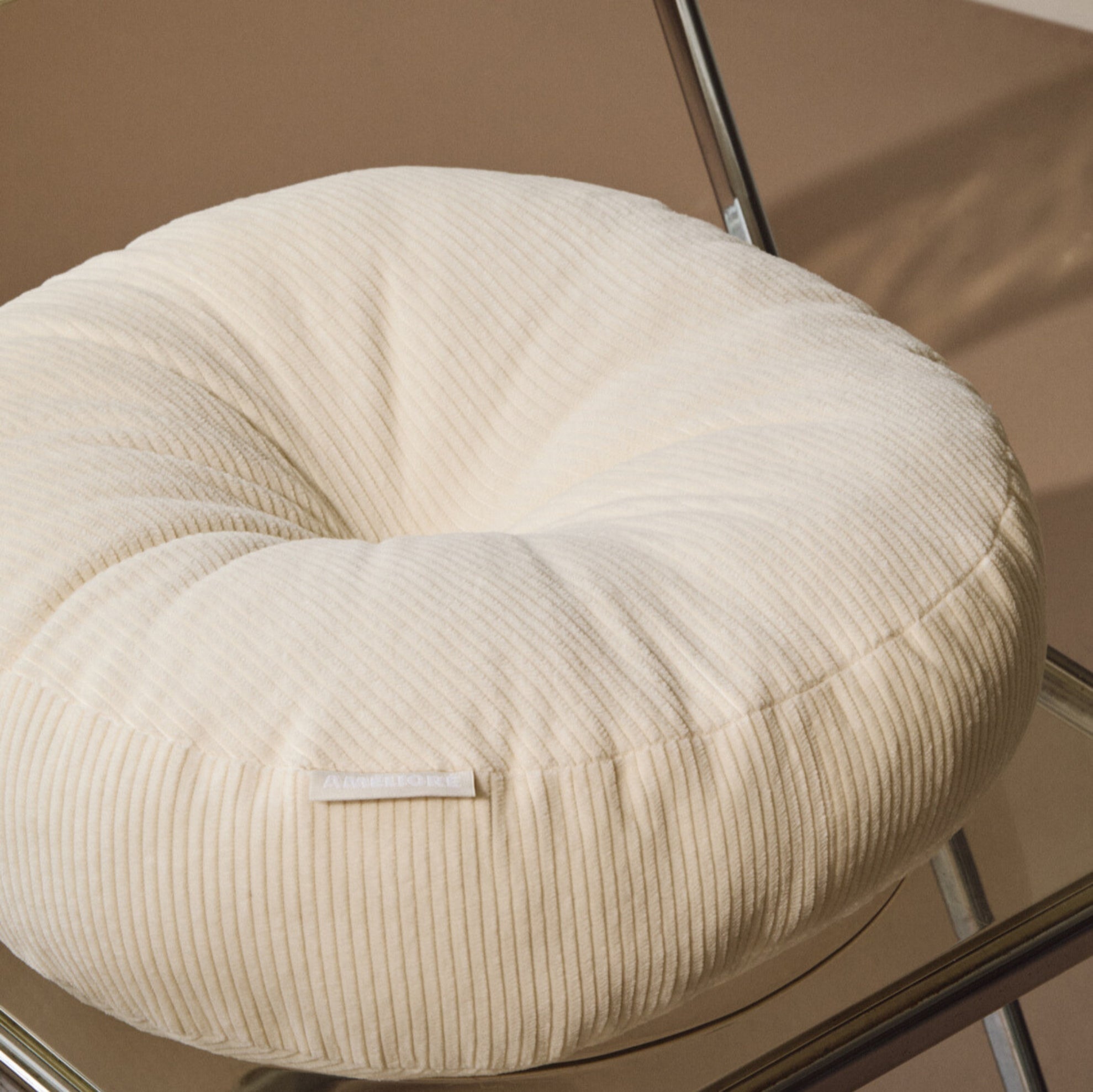 Lifestyle close up shot of cream cotton corduroy round cushion on chair