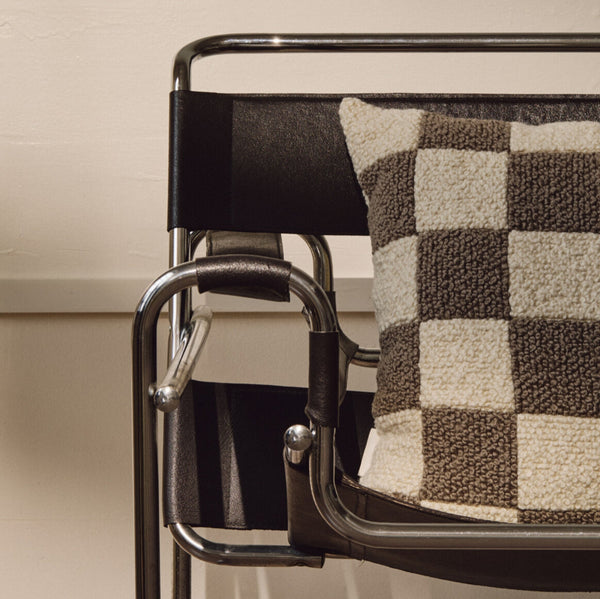 Lifestyle shot of cream and beige wool bouclé checkered square cushion on chair