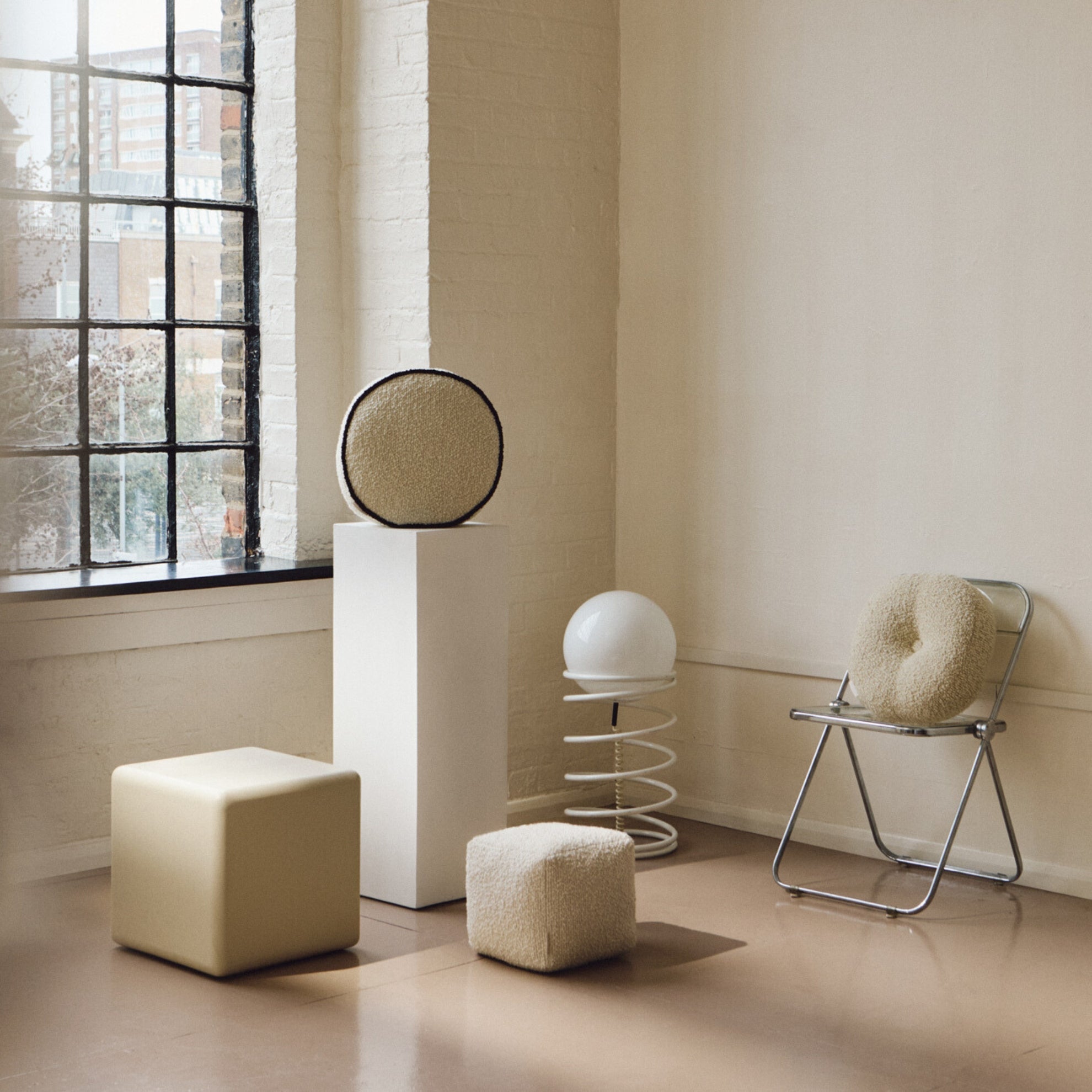 Fun lifestyle shot featuring cream wool bouclé round cushion