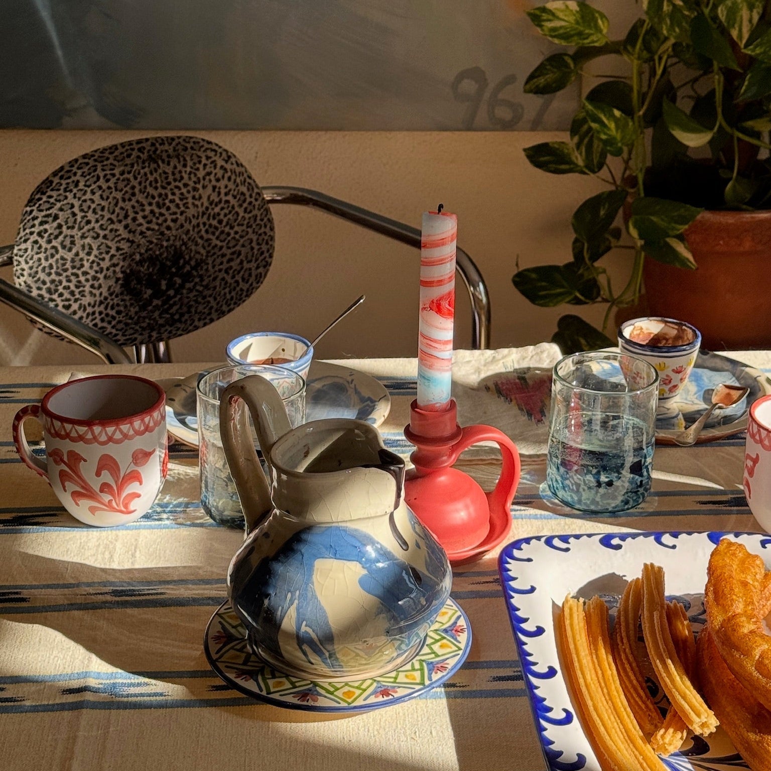 Table setting with teapot, cups, and pastries in a homey kitchen. - lifestyle