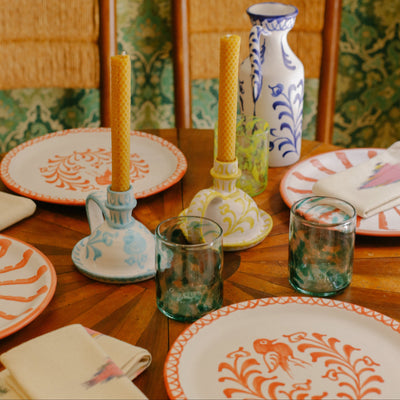 Decorative table setting with patterned plates, candles, and glasses on a wooden table. - lifestyle