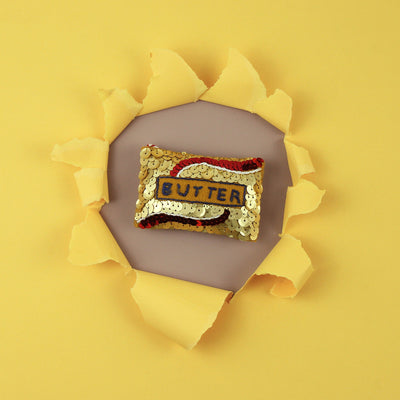 Sequin butter ornament in the centre of a punched out yellow background