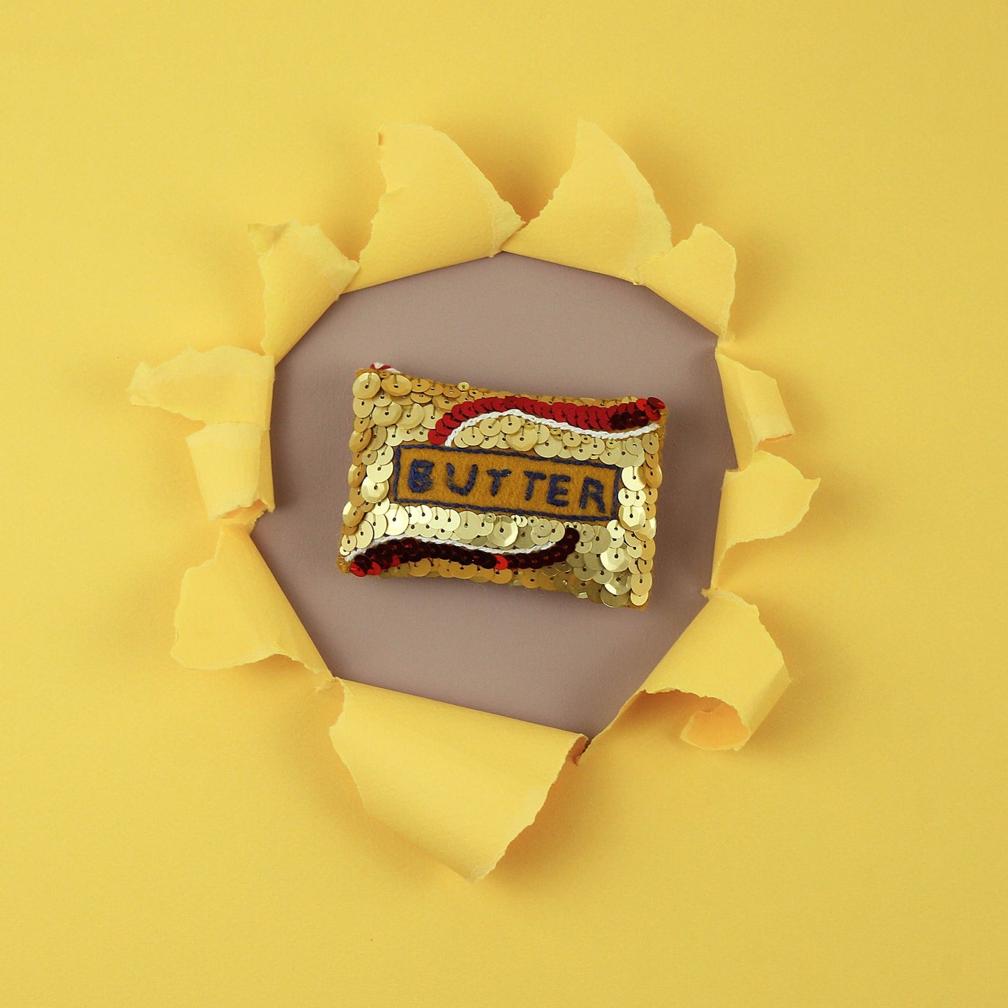 Sequin butter ornament in the centre of a punched out yellow background