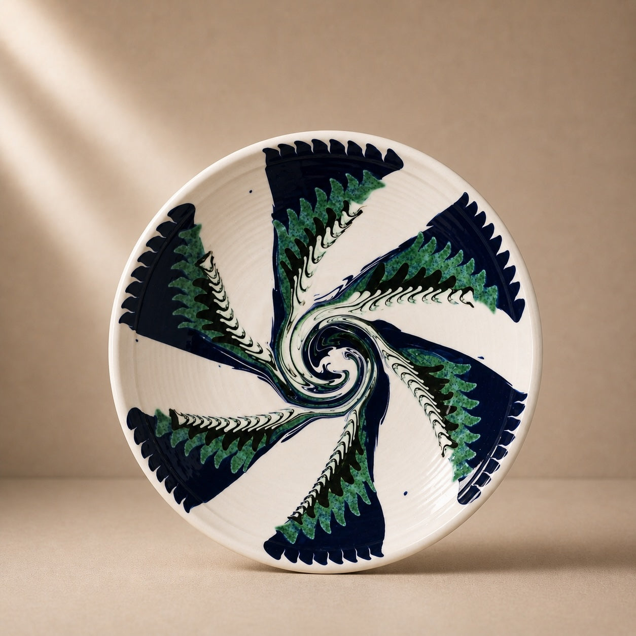 Ceramic plate with a decorative spiral design in green and black on a beige background