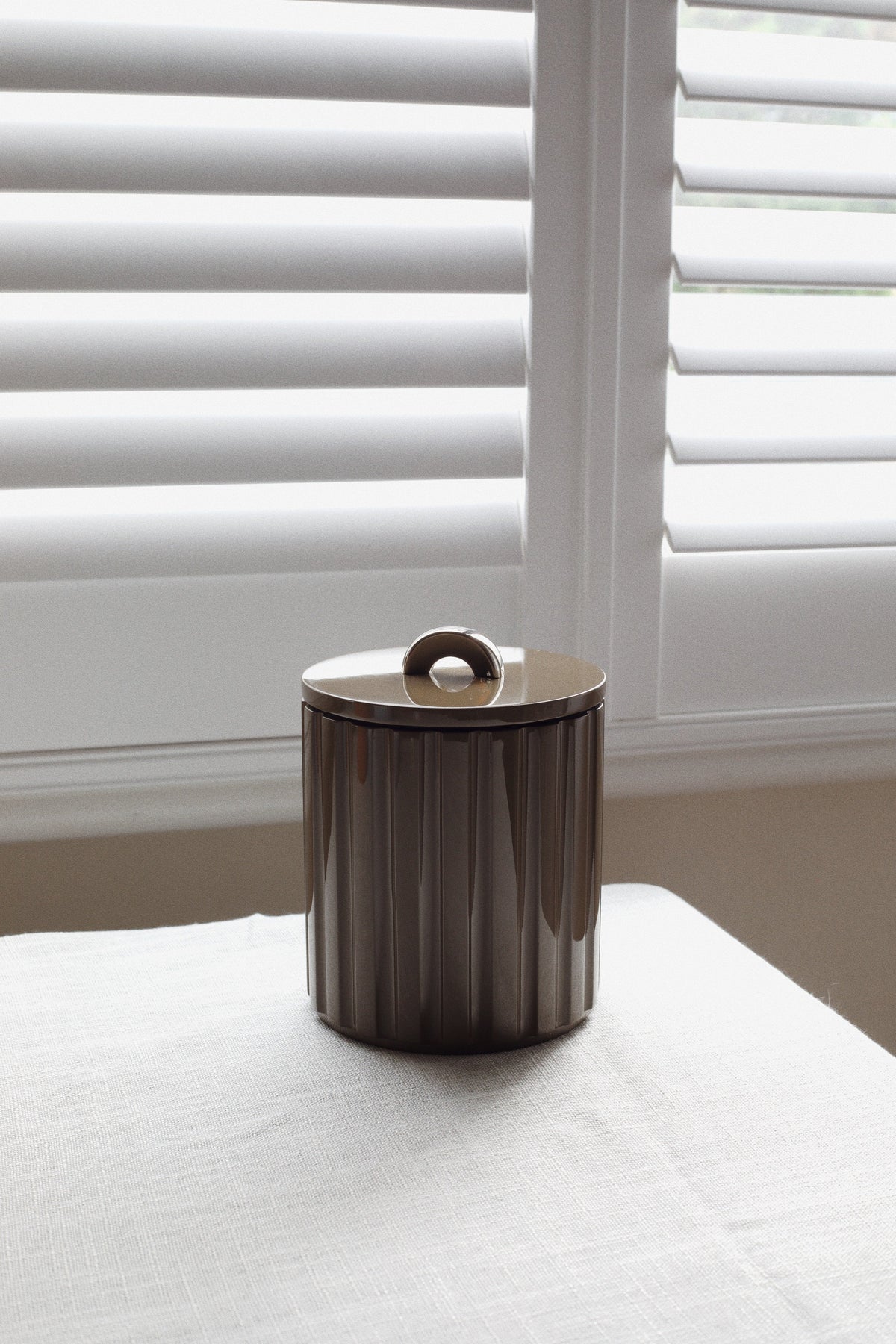 Deep espresso fluted lacquer ice bucket styled on linen for warm autumn bar cart and tablescape design.