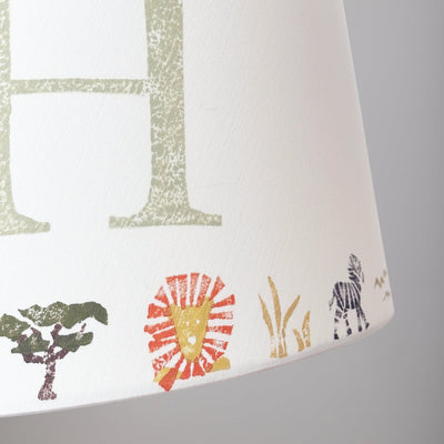 Close-up of colourful safari lampshade with lion, zebra and tree prints. Personalised lampshade detail showing handmade safari animal design, ideal for animal lampshade in kids bedroom decor.