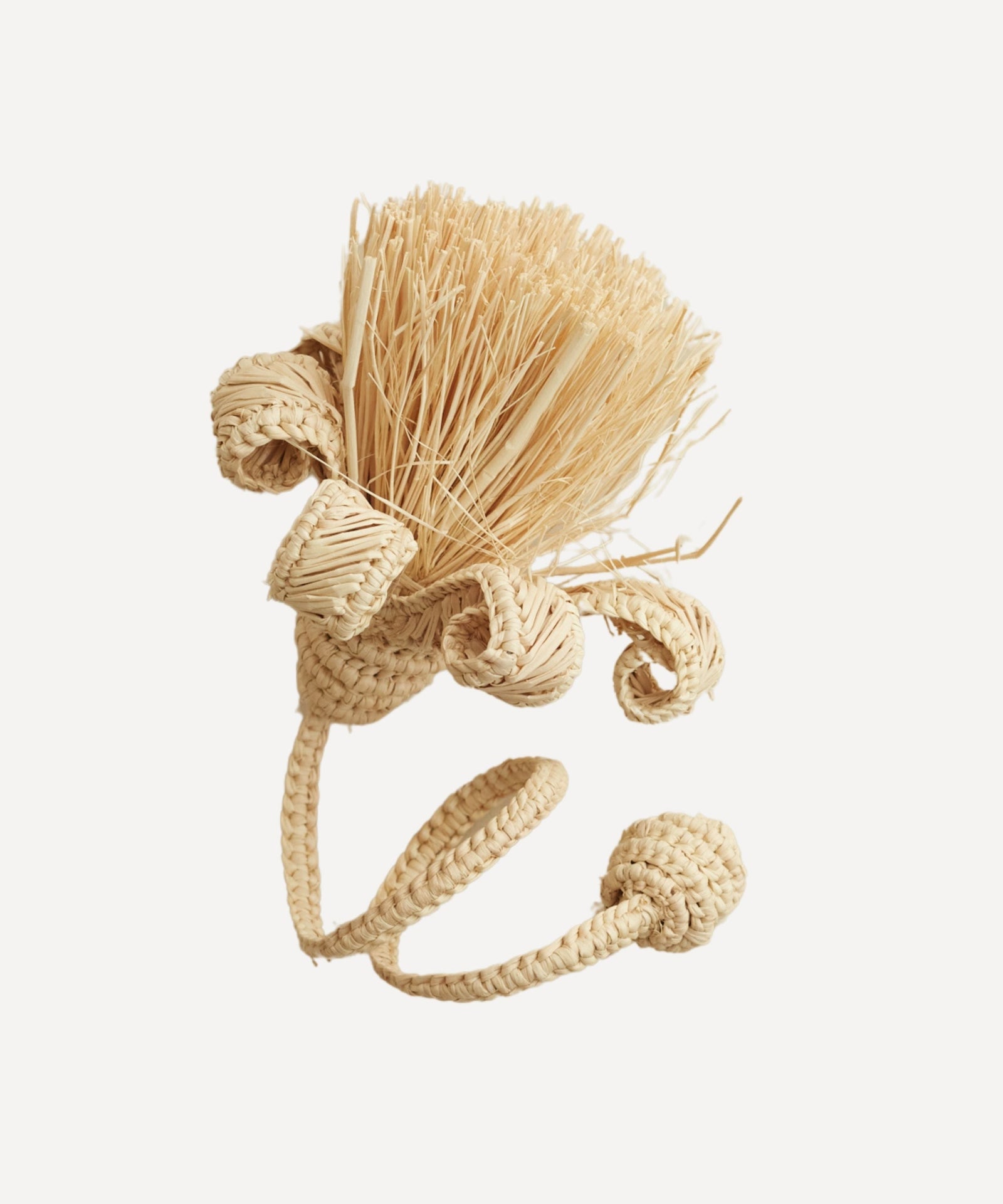 Pompon napkin ring in natural, handwoven iraca palm, holding a folded napkin