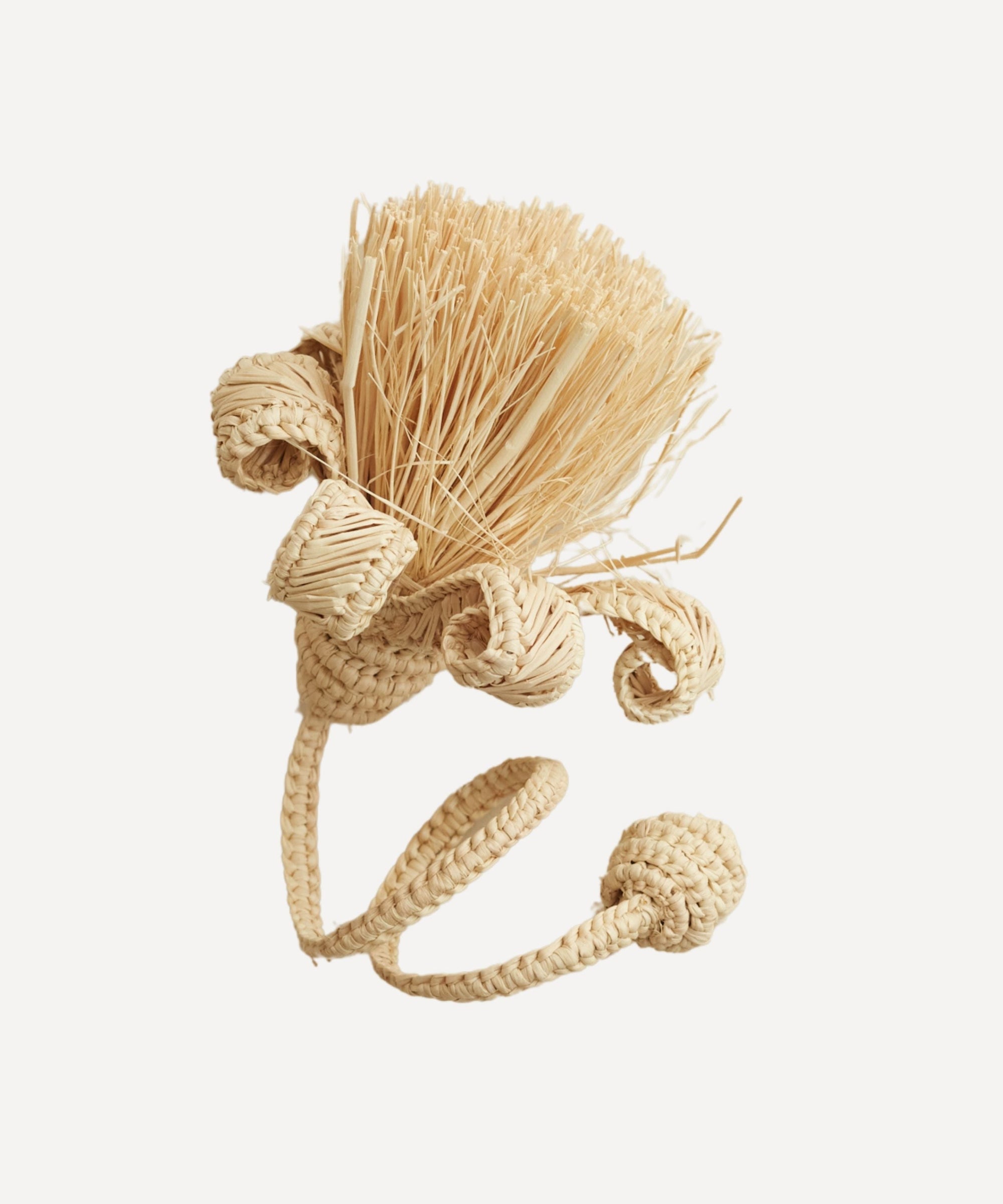 Pompon napkin ring in natural, handwoven iraca palm, holding a folded napkin