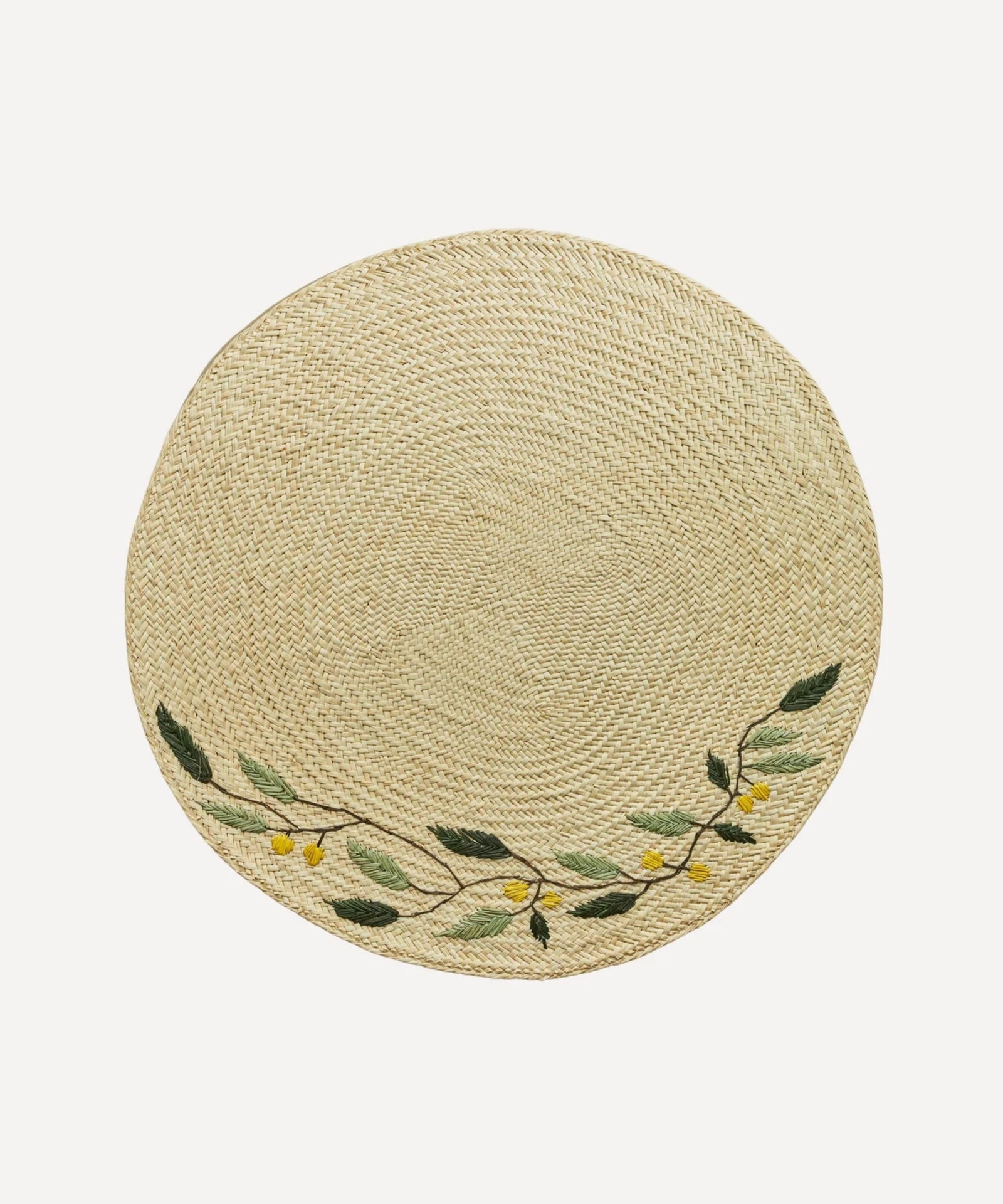 Embroidered Leaf placemat, handwoven iraca palm with leaf motif, on a table