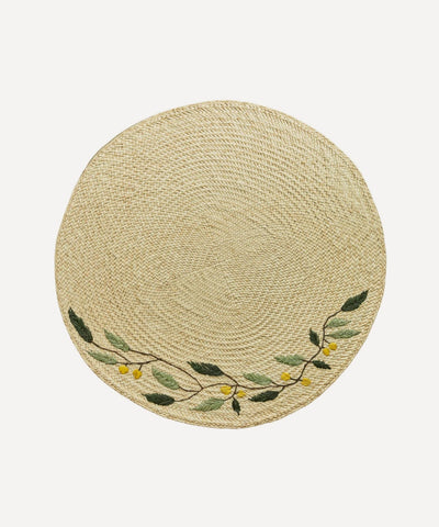 Embroidered Leaf placemat, handwoven iraca palm with leaf motif, on a table
