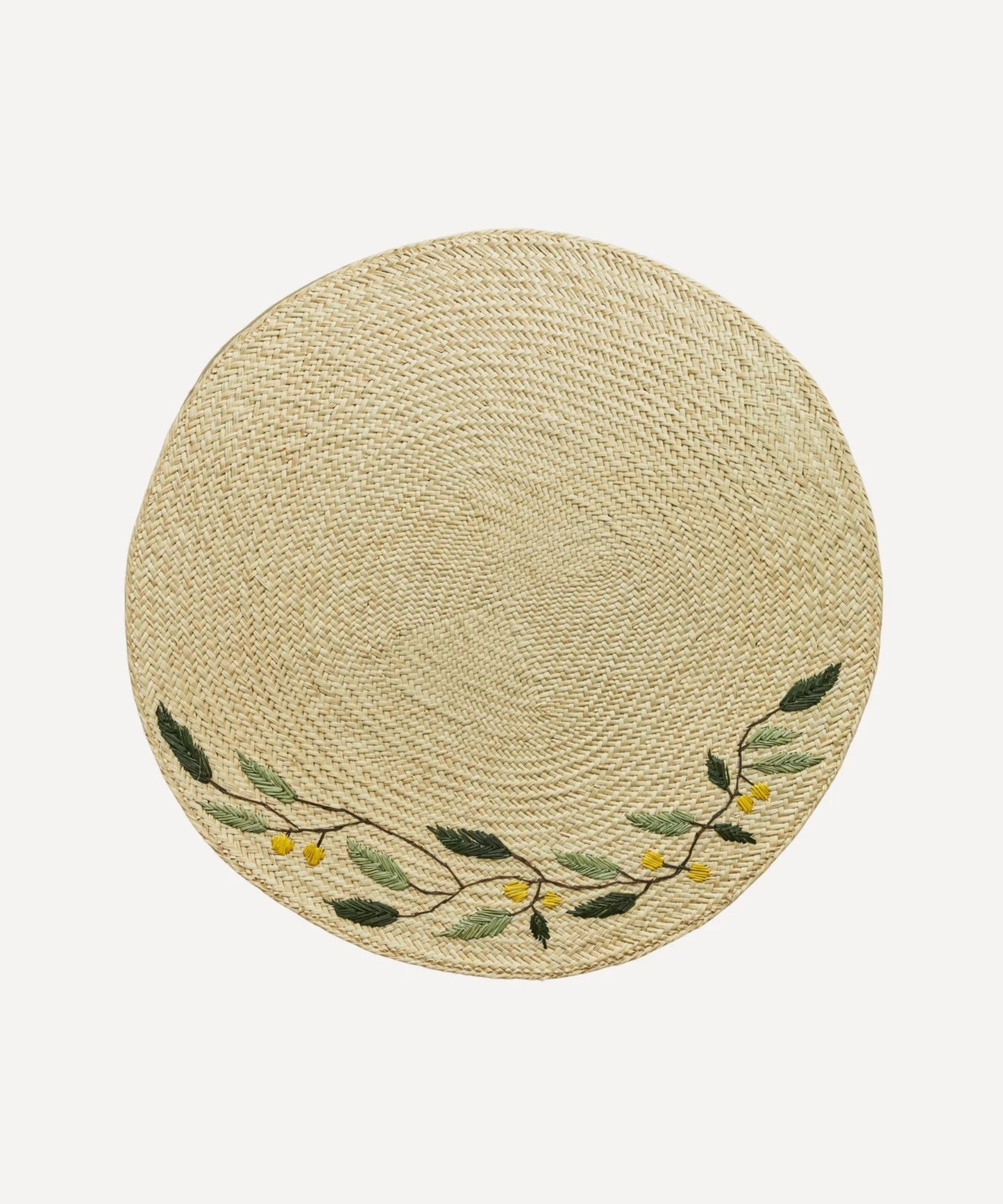 Embroidered Leaf placemat, handwoven iraca palm with leaf motif, on a table