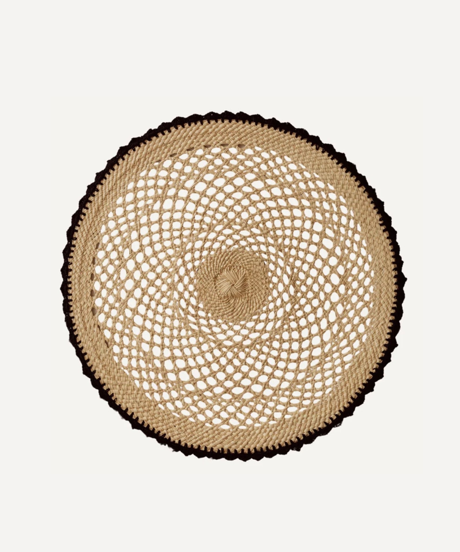 Crochet placemat in black, handwoven iraca palm, styled on a table