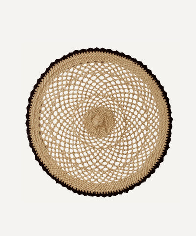 Crochet placemat in black, handwoven iraca palm, styled on a table