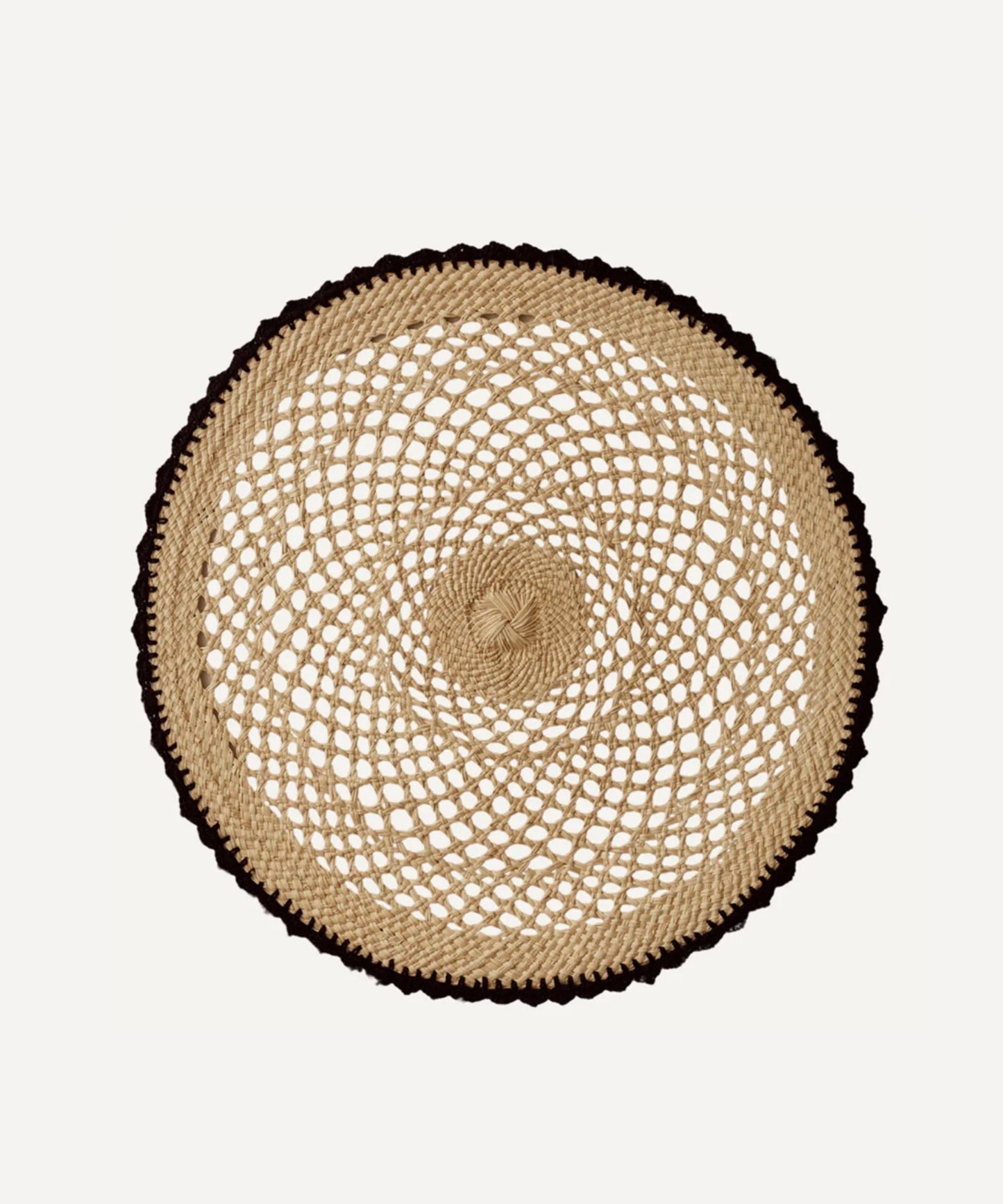 Crochet placemat in black, handwoven iraca palm, styled on a table