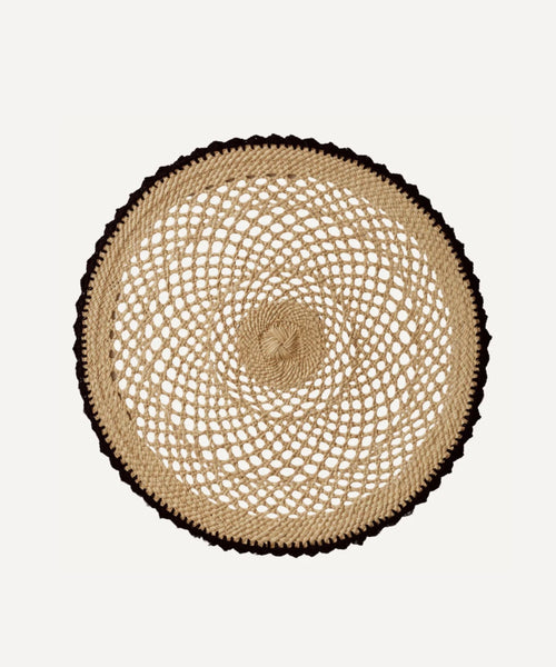 Crochet placemat in black, handwoven iraca palm, styled on a table