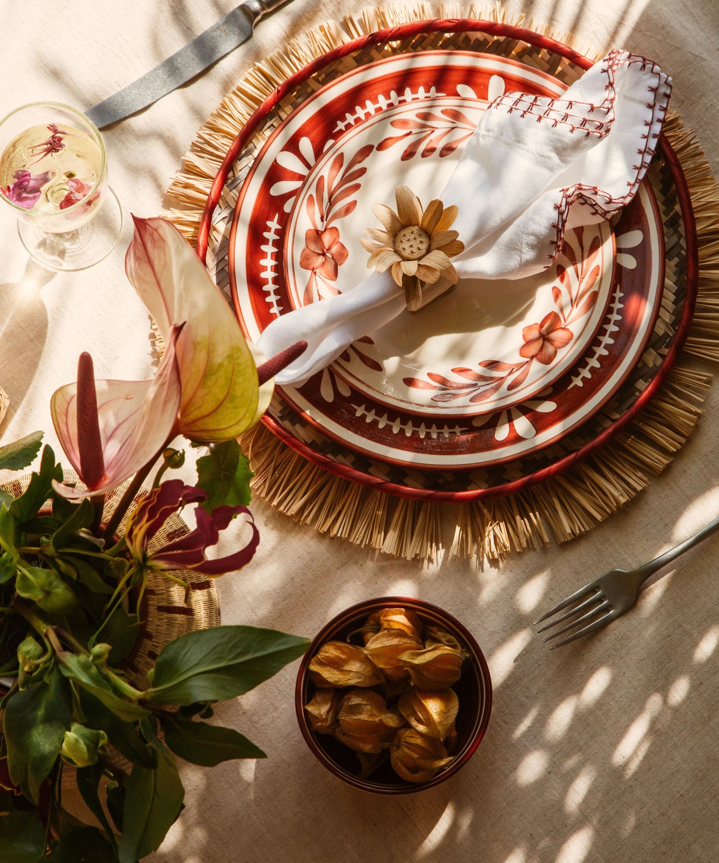 Flor Dinner Plate in Rust Red, hand-painted floral ceramic — on a table setting