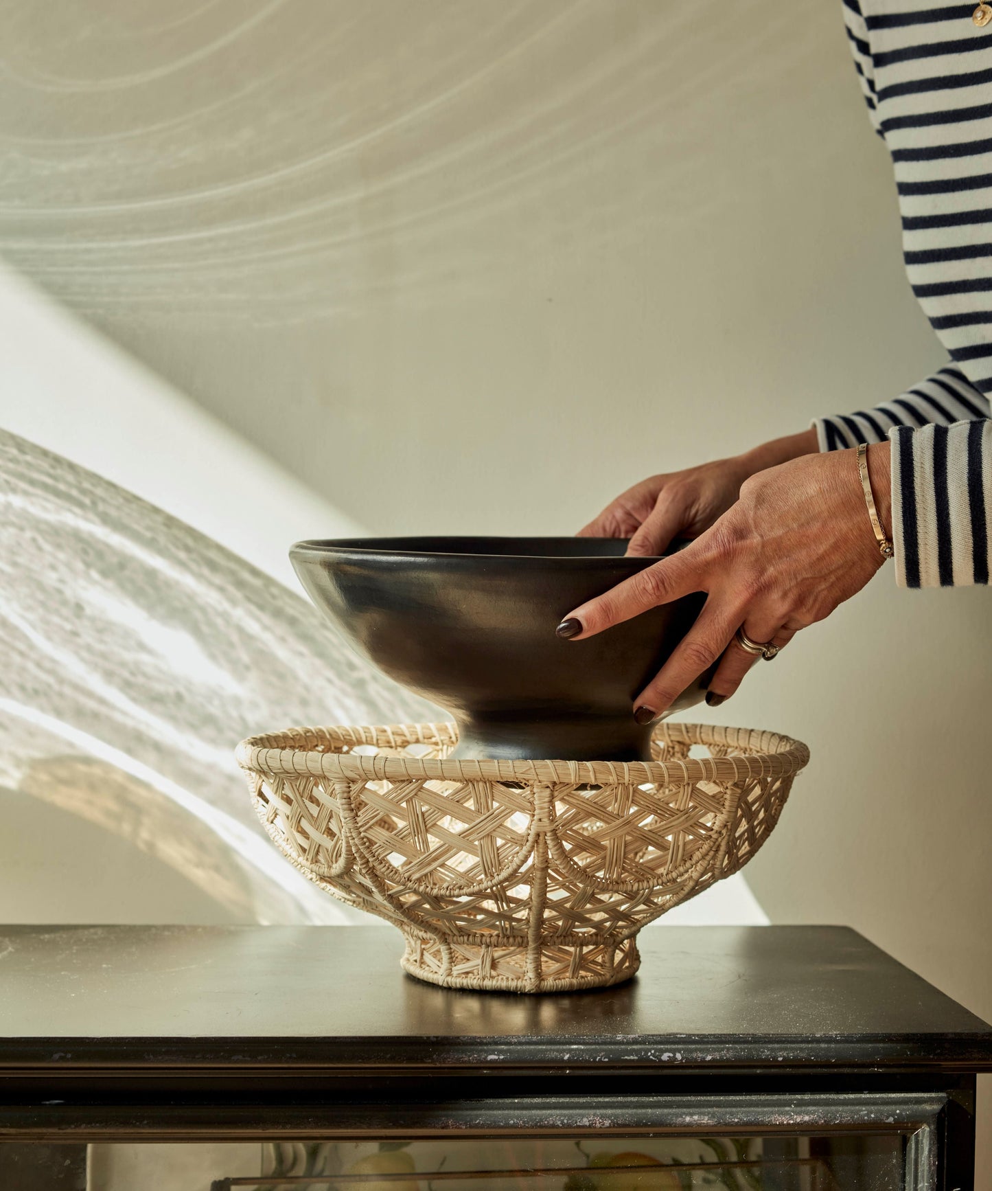 Amaranta Oval Bowl lifestyle - black clay bowl and woven Iraca base