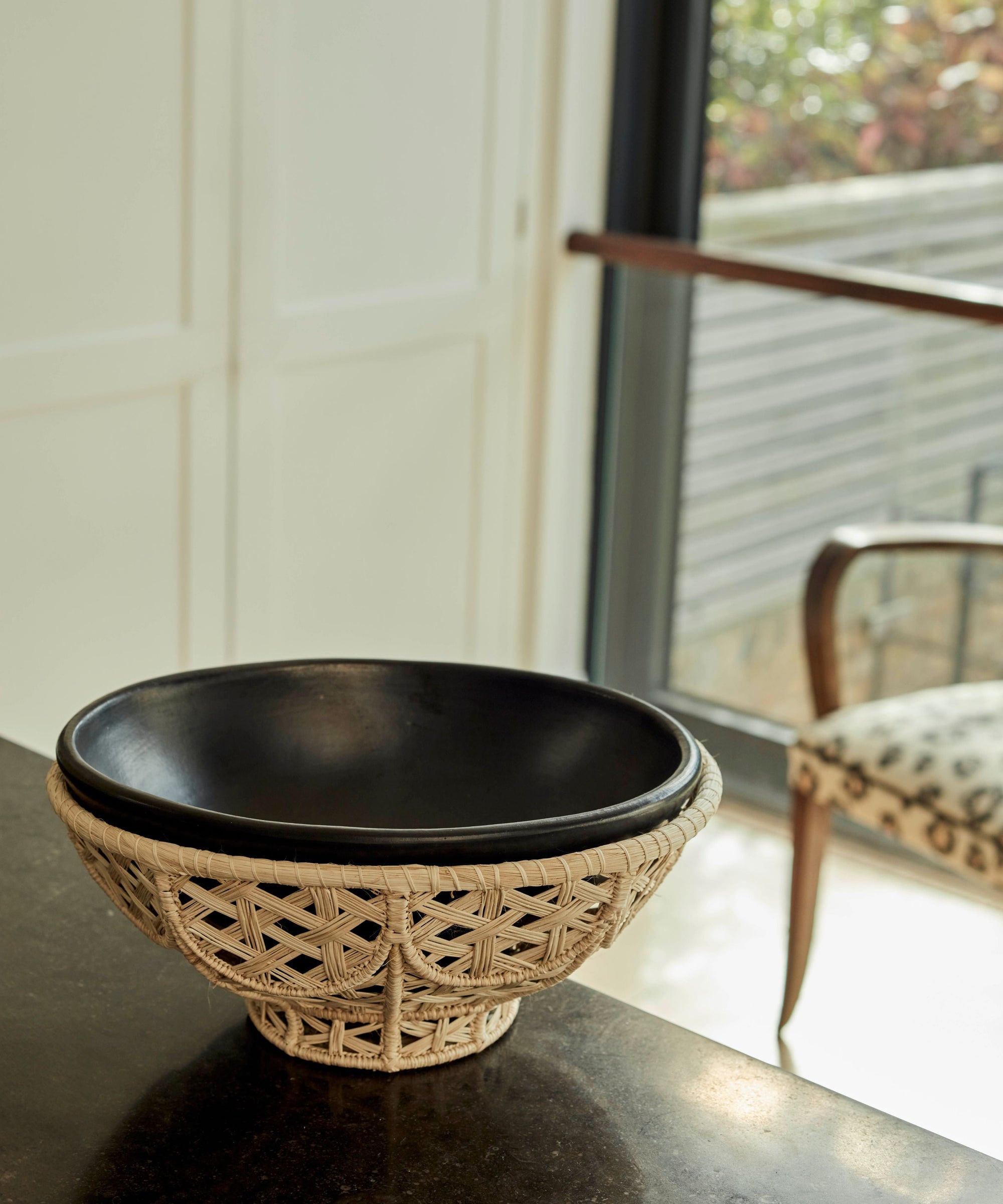 Amaranta black-clay bowl lifted from its handwoven Iraca palm nest