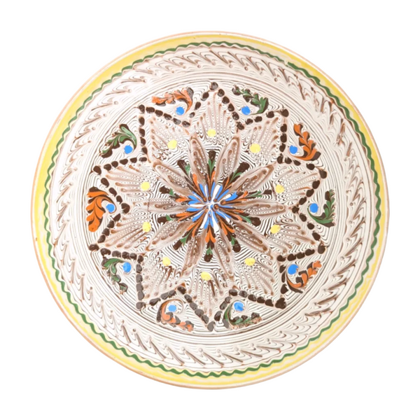 A large, handcrafted ceramic serving plate with a geometric and floral pattern, predominantly in ecrus and whites, with touches of other colors.