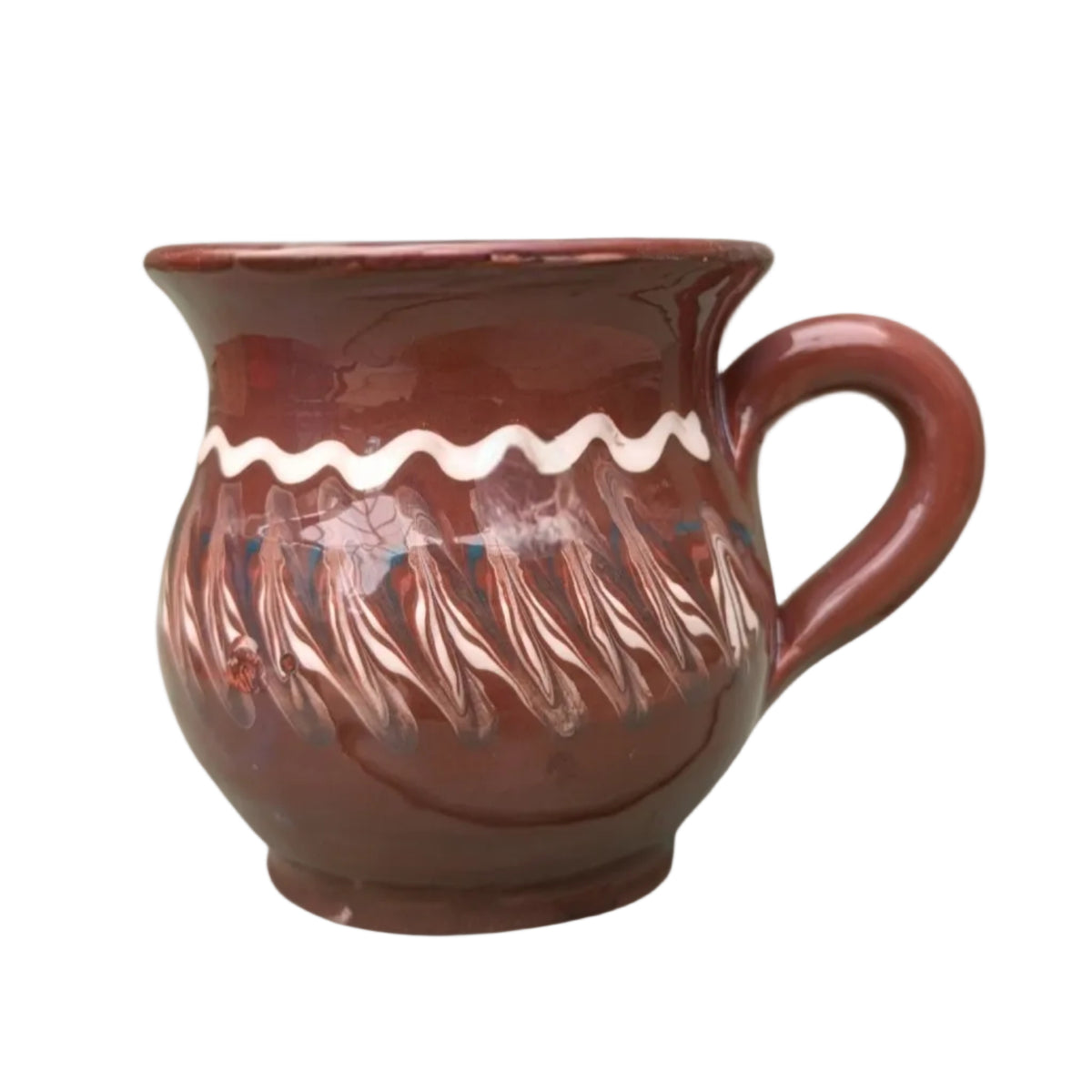 Handmade dark chocolate Romanian ceramic mug with traditional folk decoration on outdoor café table