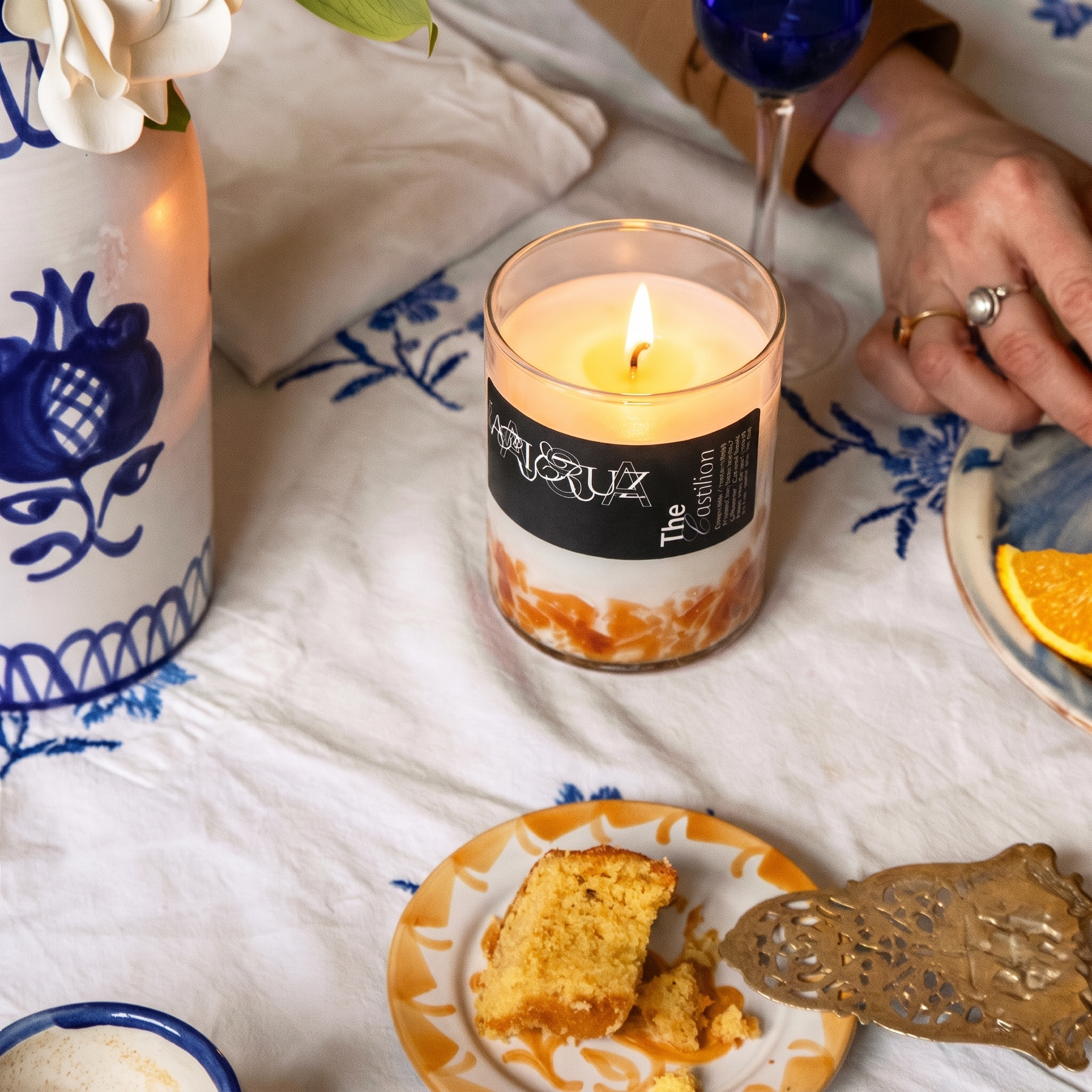 candle in orange halfway glass set in a blue table. - lifestyle