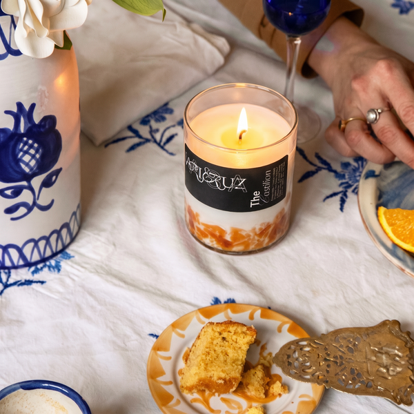 candle in orange halfway glass set in a blue table. - lifestyle
