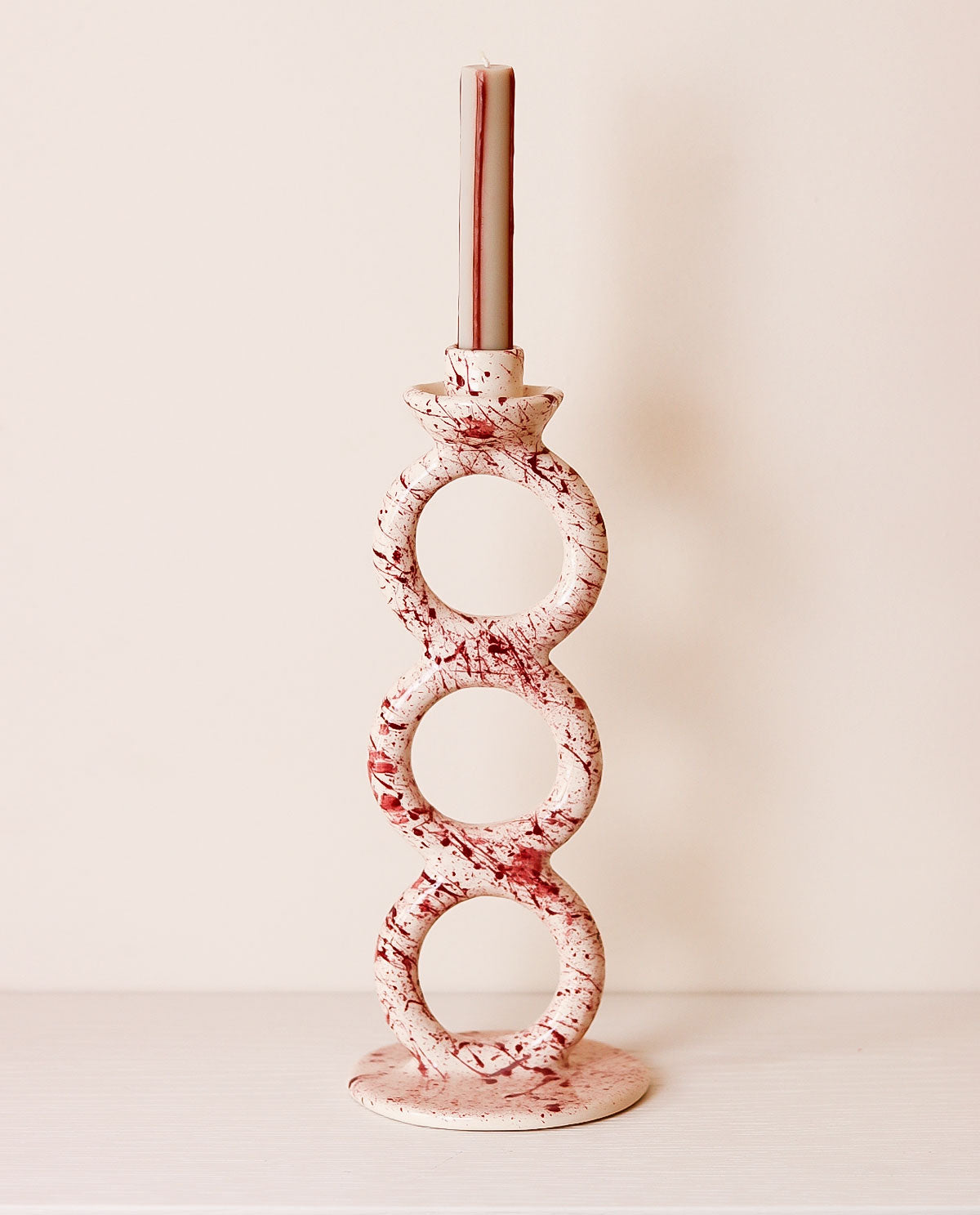Decorative candle holder with purple and white pattern on a plain background