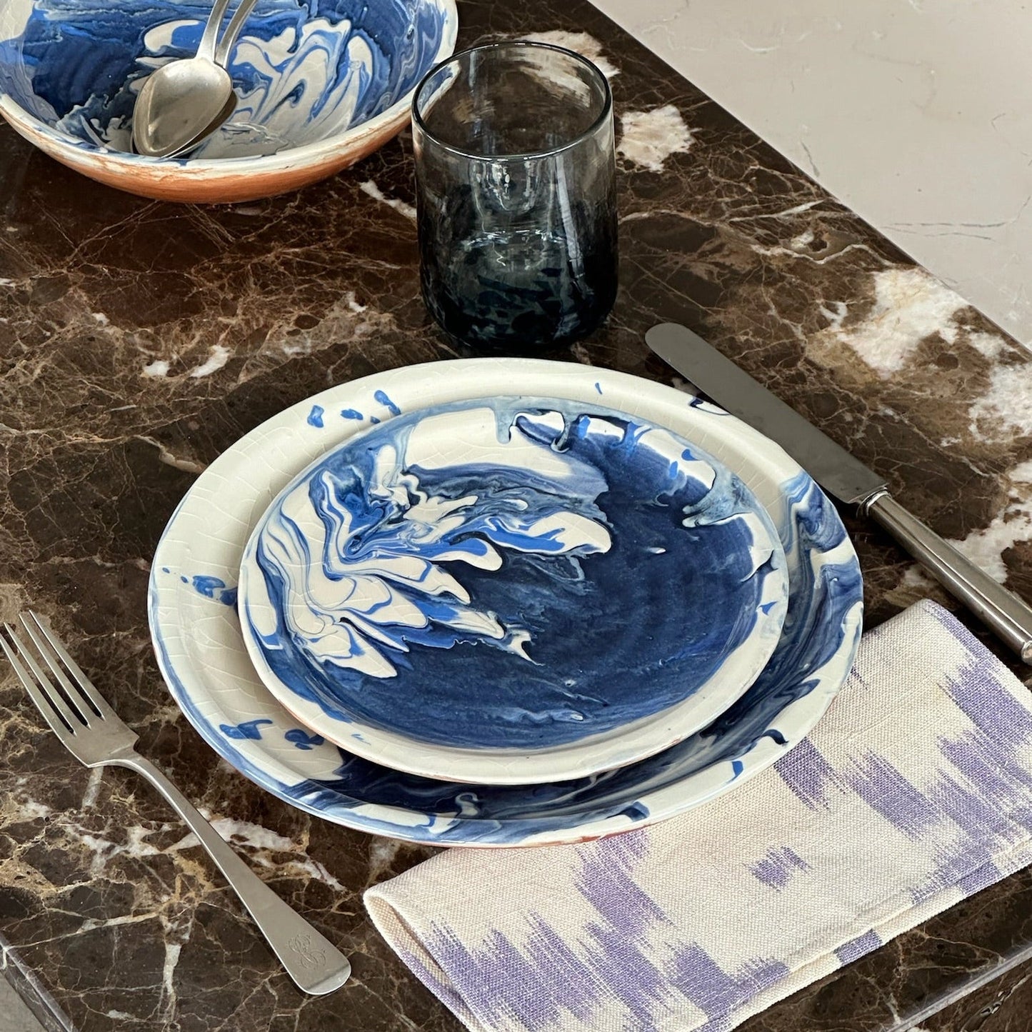 Blue and white marbled plates with silverware on a marble surface - lifestyle