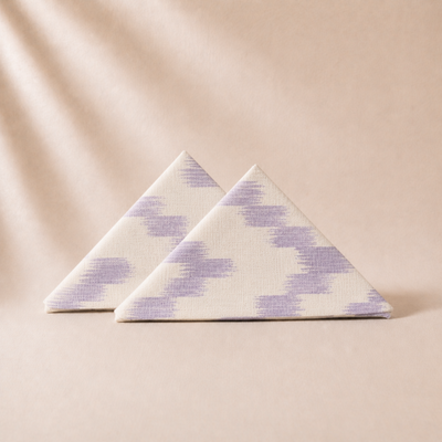 Two triangular napkins with a purple pattern on a beige background