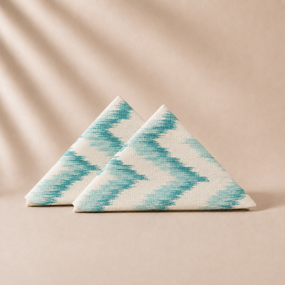 Two triangular napkins with a blue and white pattern on a beige background