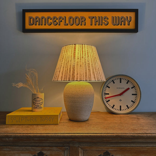 Striped lampshade glowing warmly in evening light, creating bold striped lighting. A handmade empire lampshade that doubles as a bold lampshade statement piece.