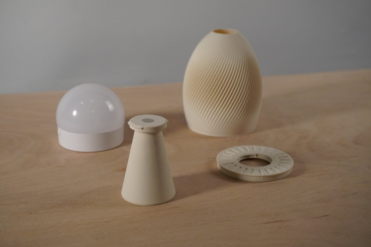 Set of ceramic vases and components on a wooden surface with a neutral background