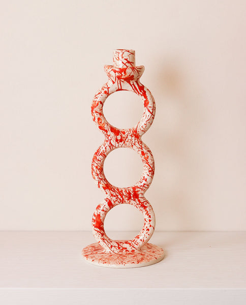 Decorative candle holder with red and white pattern on a light background