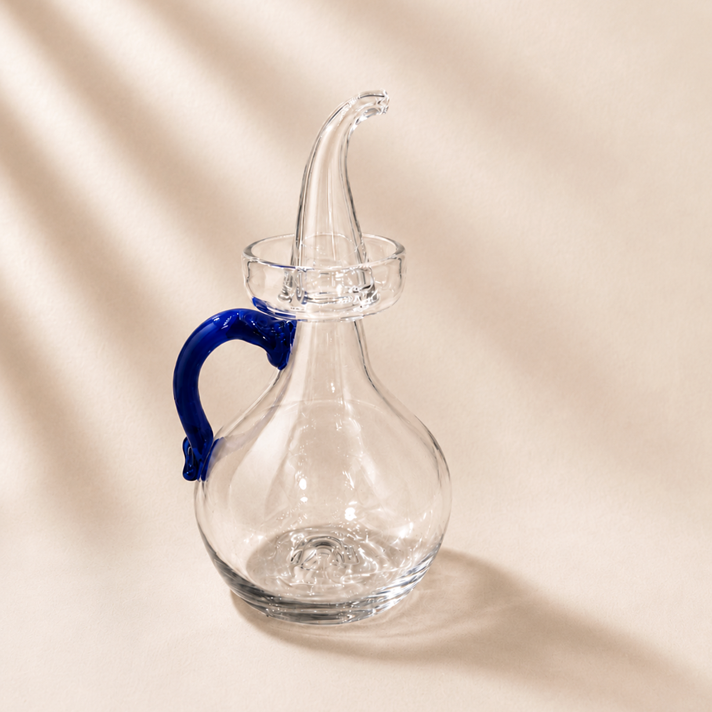 Olive cruet with a blue handle on a beige background